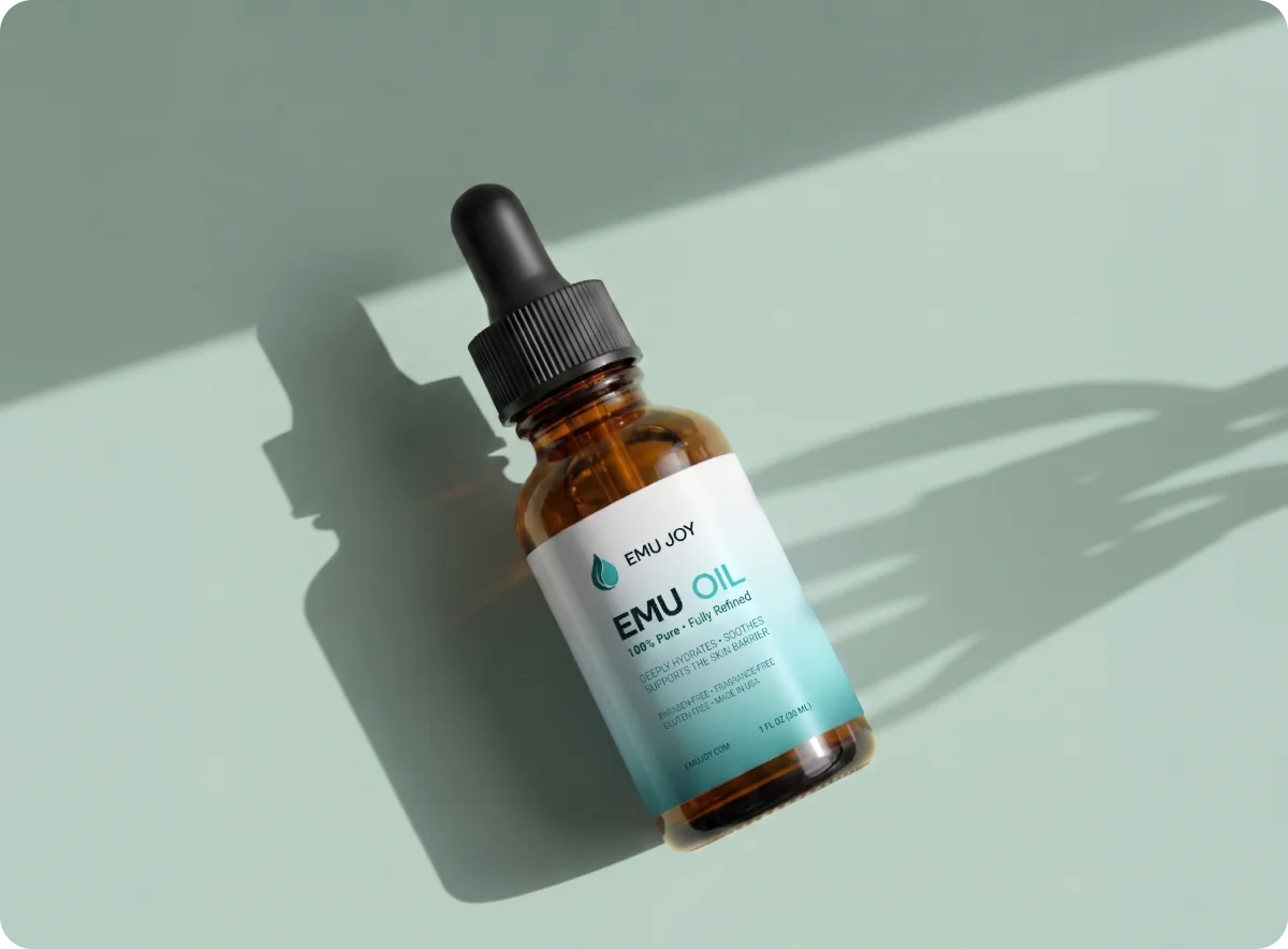 An Emu Joy pure emu oil dropper bottle lying on a sage green surface