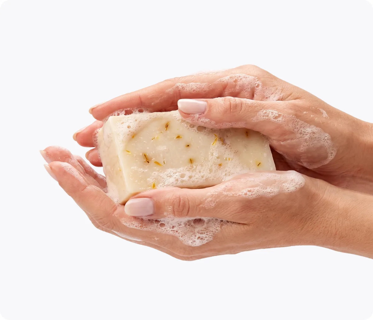 Two hands lathering the Emu Joy Emu Oil Soap bar, calendula petals visible in the bar