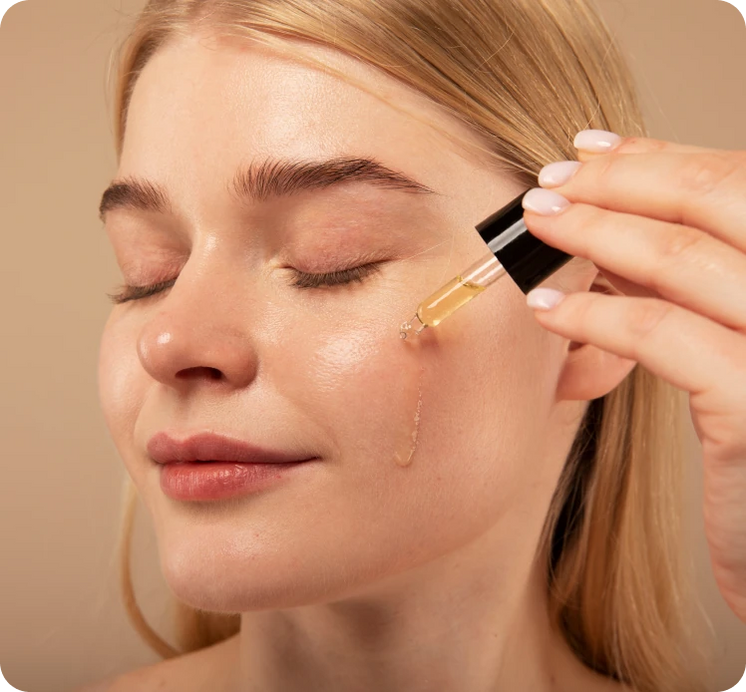 Woman applying facial oil to her cheek with a dropper