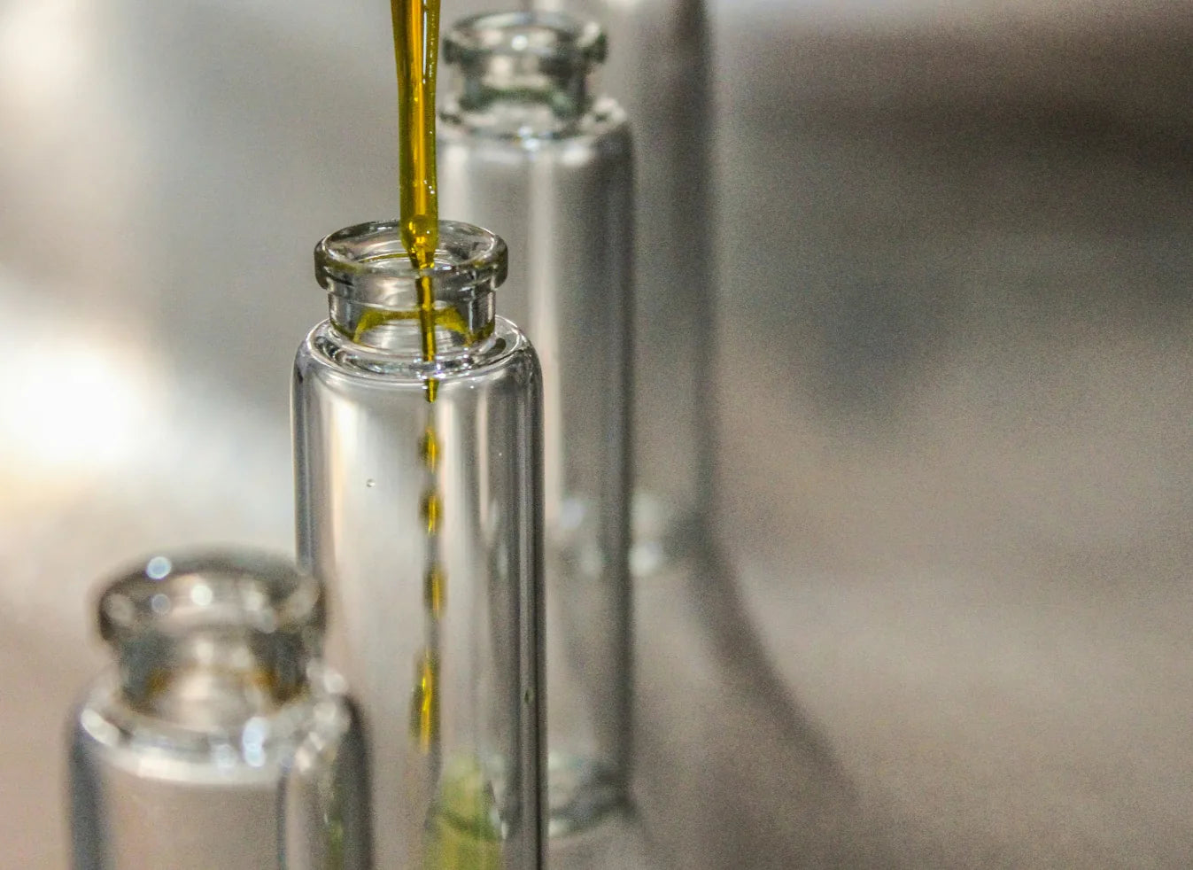 Fresh golden emu oil pouring into clear glass vials