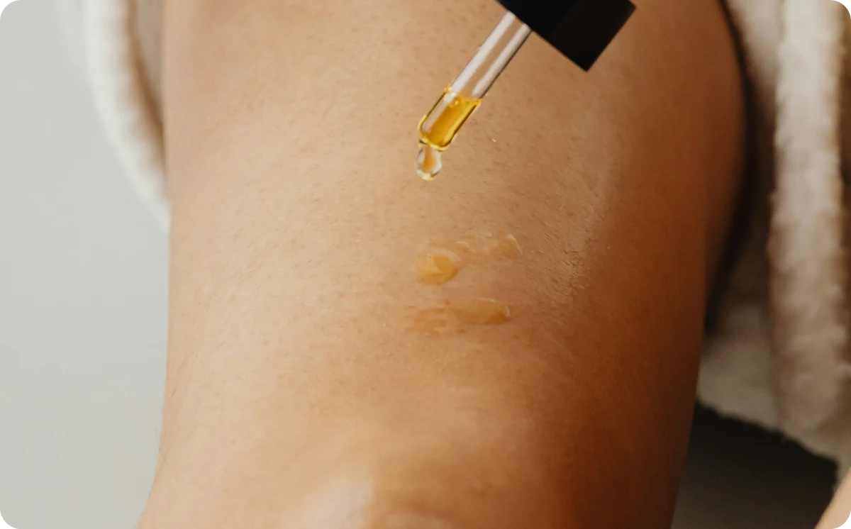 Dropper applying golden emu oil onto smooth skin