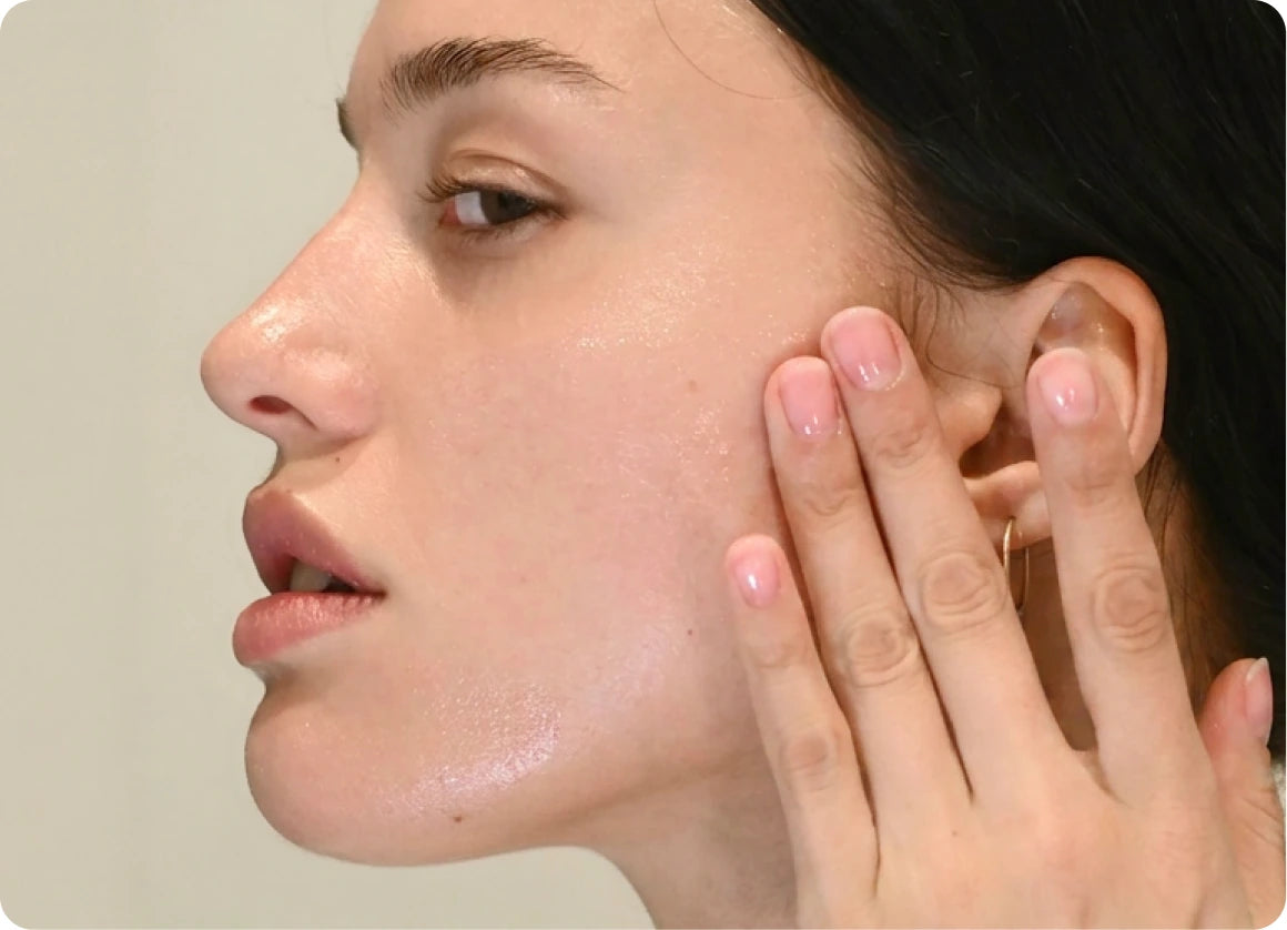 Close-up of a woman pressing emu oil into her cheek with her fingertips