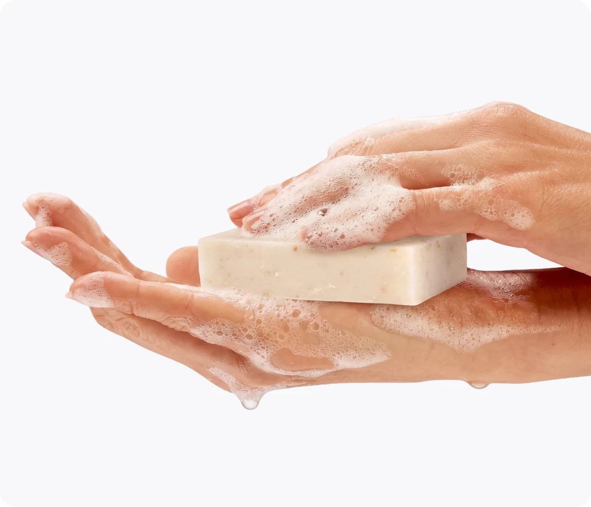 Two hands working the Emu Joy oatmeal bar into a soft, creamy lather